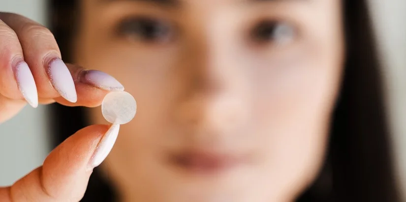 Close-up of a woman's hand with purple nail polish holding a card or object, with part of her hair visible.